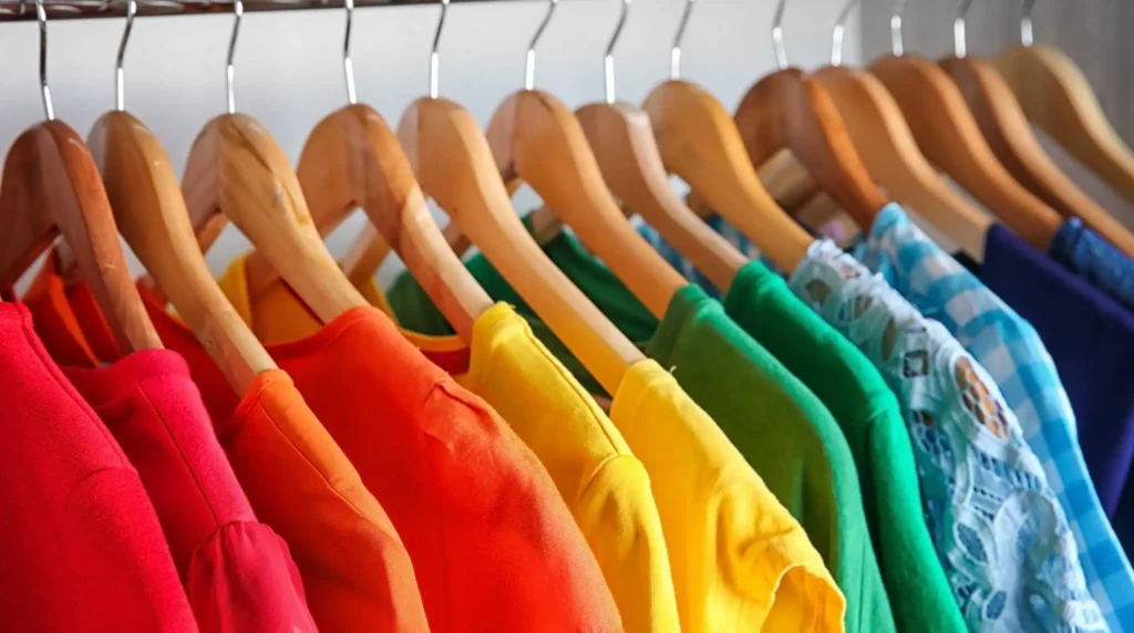 Current image: Colorful tops in red, orange, yellow, green, and blue on wooden hangers in a row Sensory Clothing Autism Adults Summer Breathable