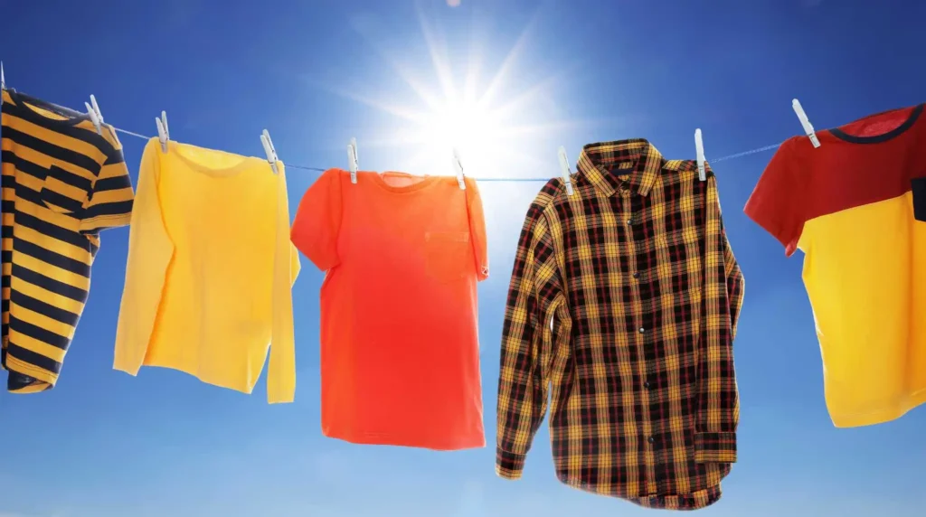 Current image: Vibrant yellow, orange, and plaid shirts hang from a clothesline against a bright blue sky with sun rays shining through, Sensory Clothing Autism Adults Summer Breathable